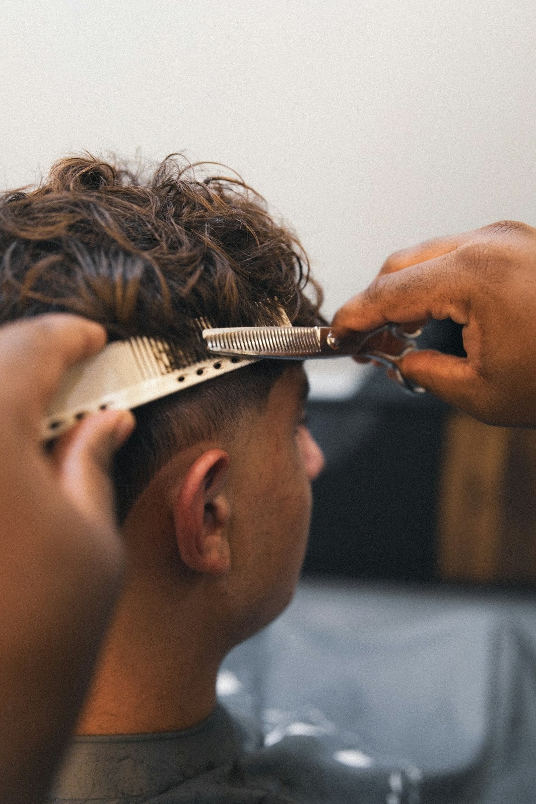 A barber uses shears and a comb to trim hair.