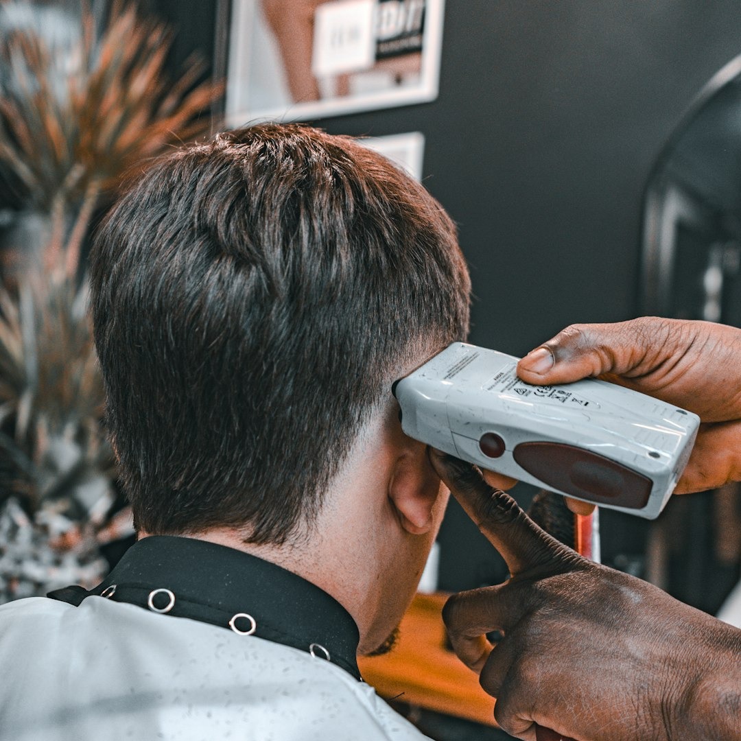 Barber uses clippers to trim a client's hair.