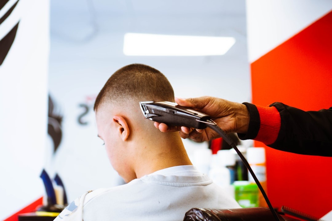A barber uses electric clippers to trim a client's hair.